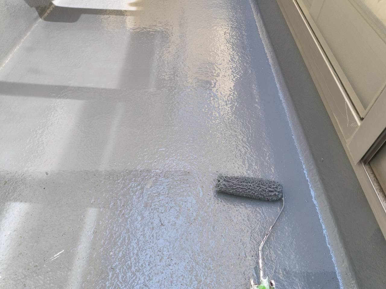 バルコニー床にトップコート1回目を塗装中